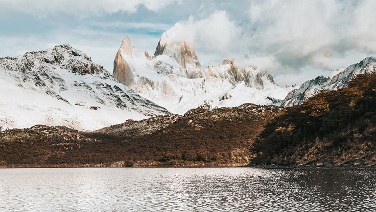 Water en grote keien op de voorgrond met op de achtergrond de besneeuwde berg Cerro Chaltén.