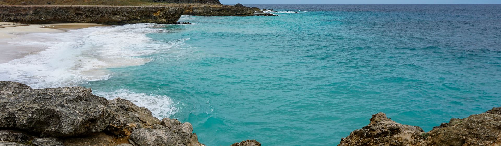 Dos Playa Beach op Aruba. Vanaf rotsen uitzicht op een klein strand en blauwe zee.