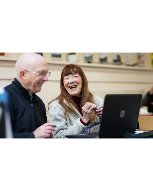 Lachende gepensioneerde vrouw achter laptop